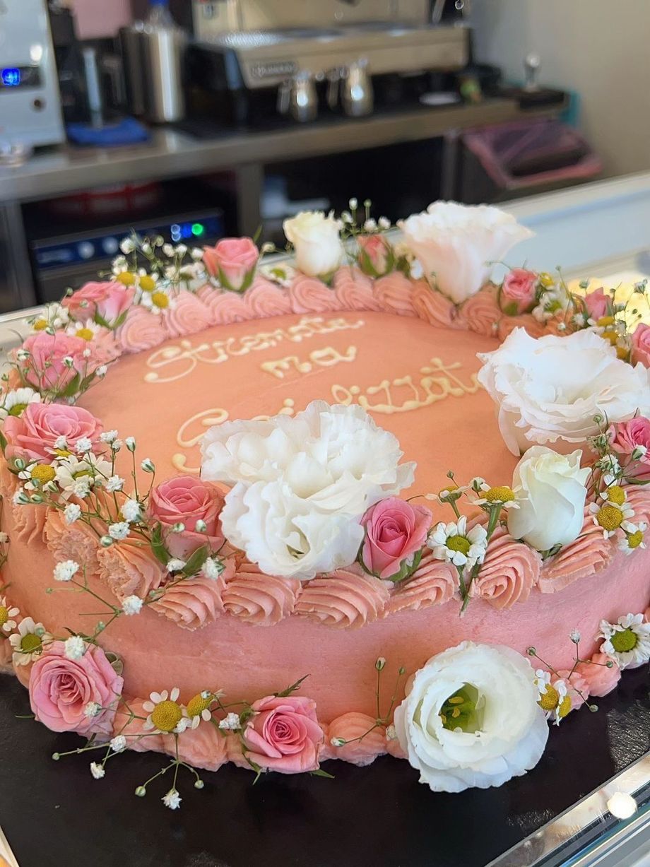 Torta rotonda alla pesca decorata con fiori rosa e bianchi su un bancone