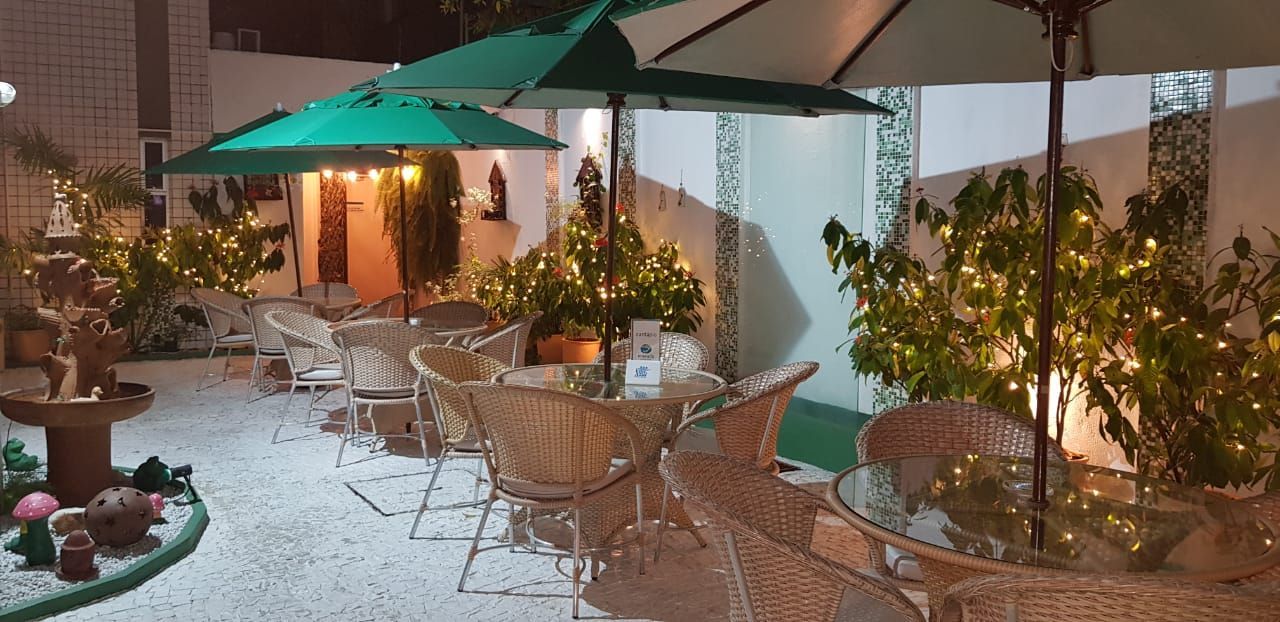 Um pátio com mesas, cadeiras e guarda-sóis à noite. Vila Azul Praia Hotel
