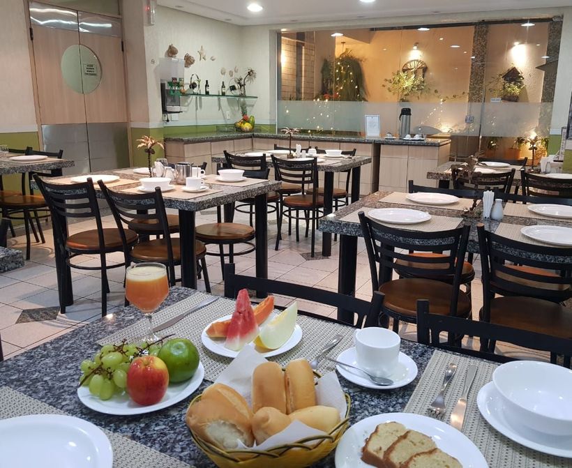 Um restaurante cheio de mesas, cadeiras e pratos de comida. Vila Azul Praia Hotel