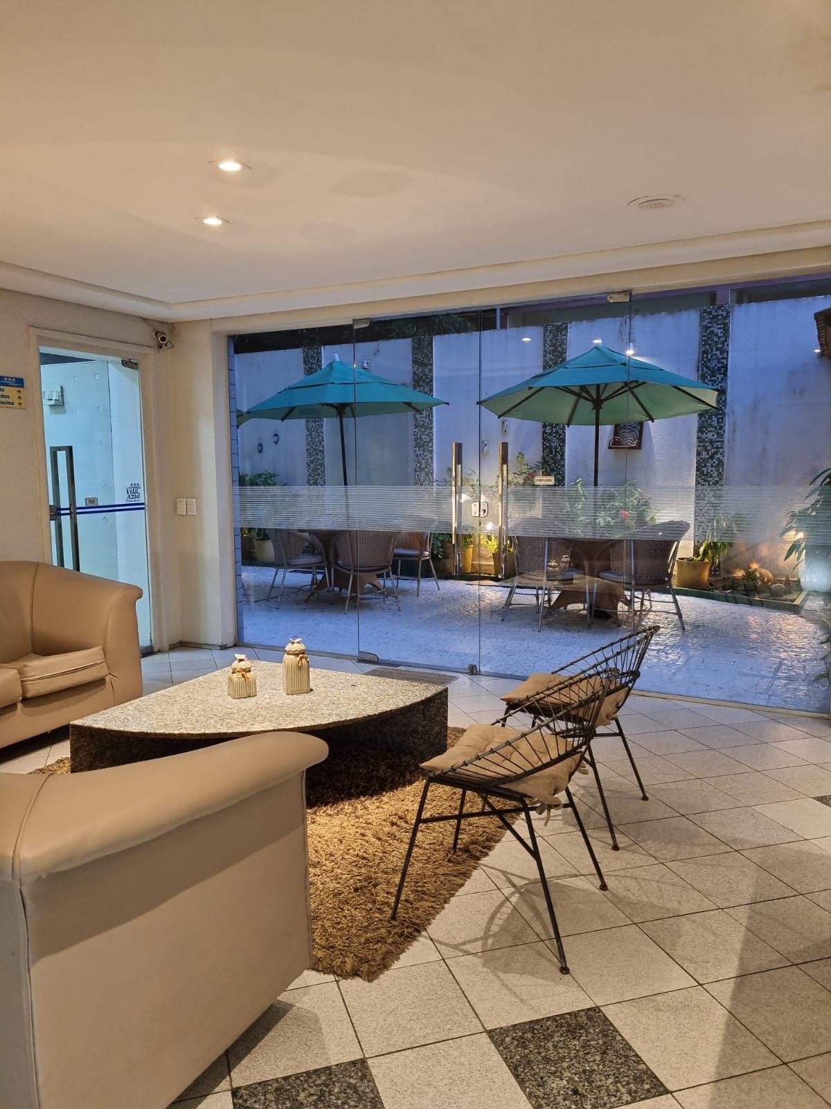 Uma sala de estar com sofá, cadeiras, mesa de centro e guarda-sóis Vila Azul Praia Hotel