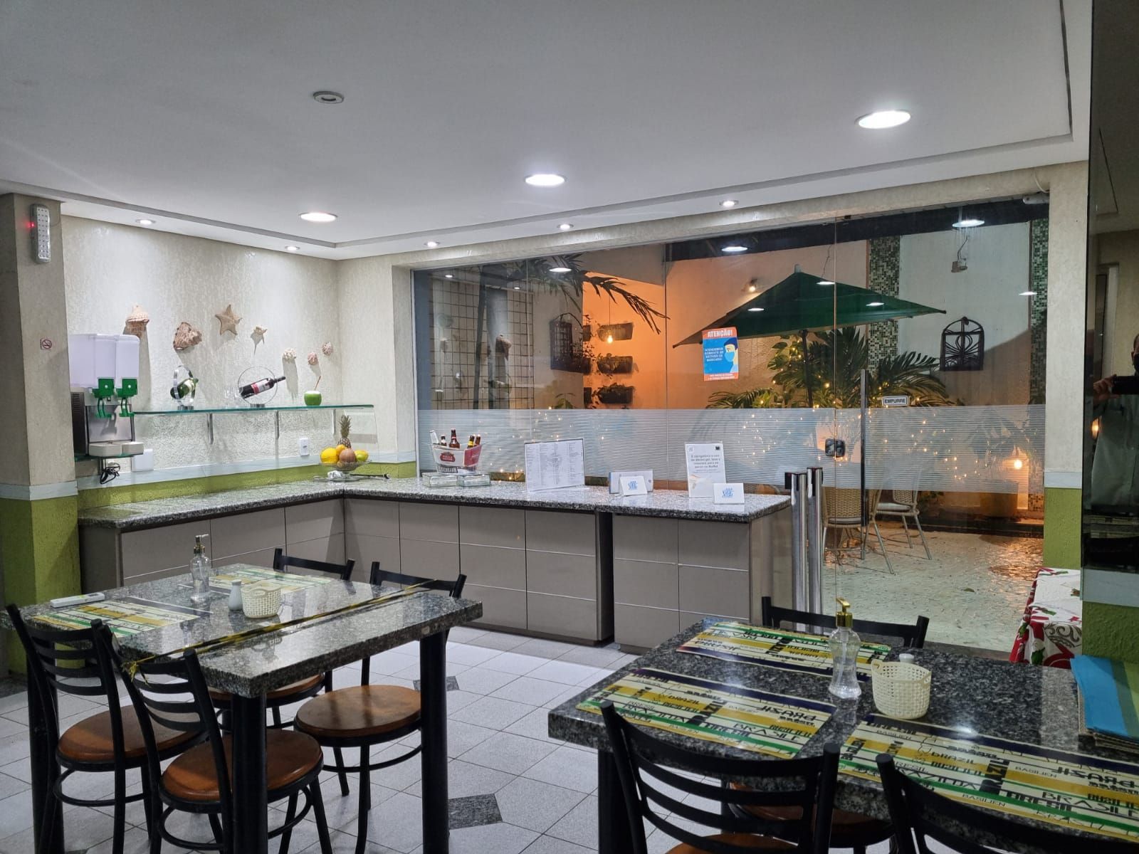 Um restaurante com mesas e cadeiras e uma grande janela. Vila Azul Praia Hotel