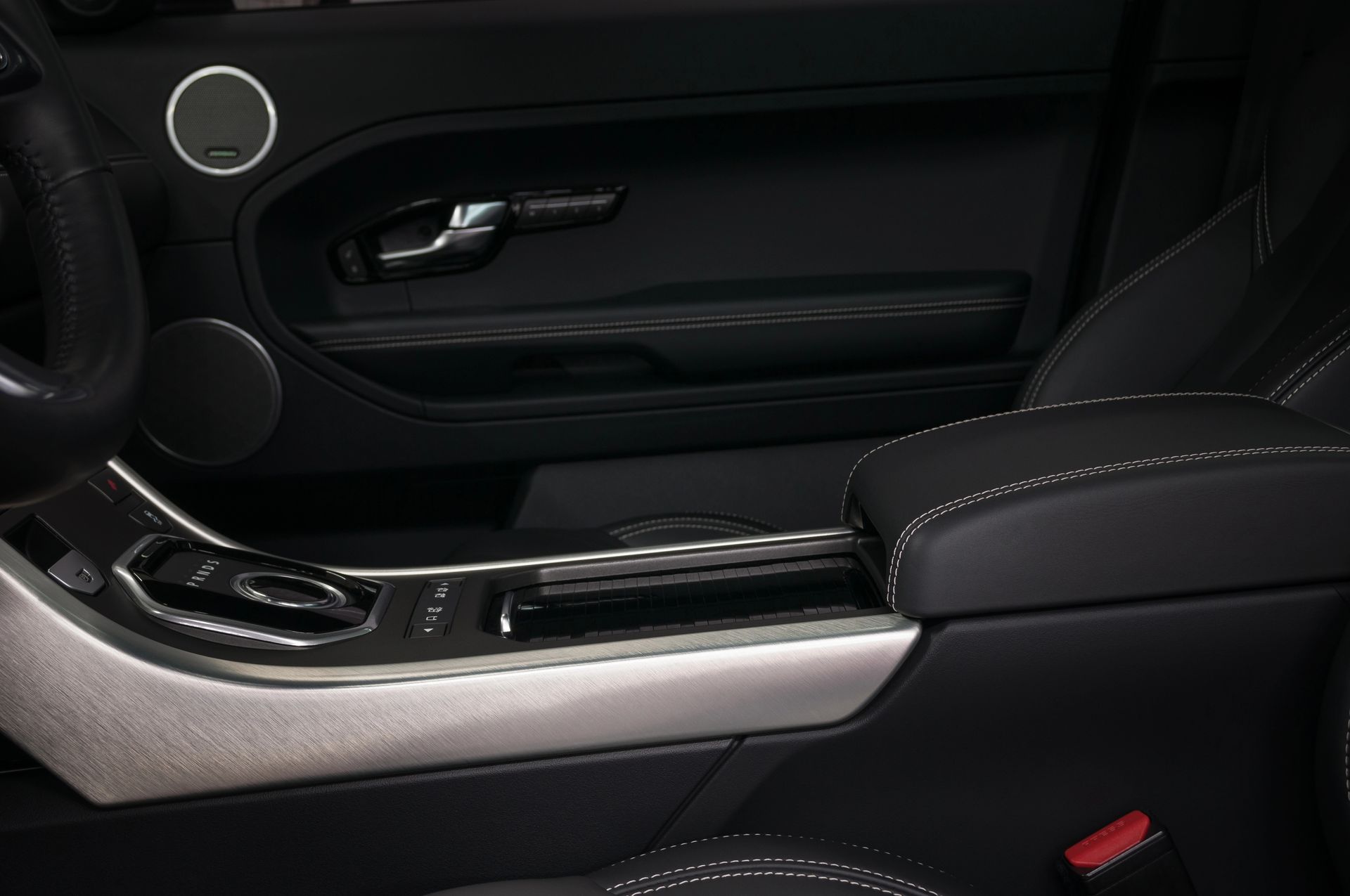 Interni di un'auto moderna, con console centrale, bracciolo e pannello della portiera rivestiti in pelle nera e finiture argentate.