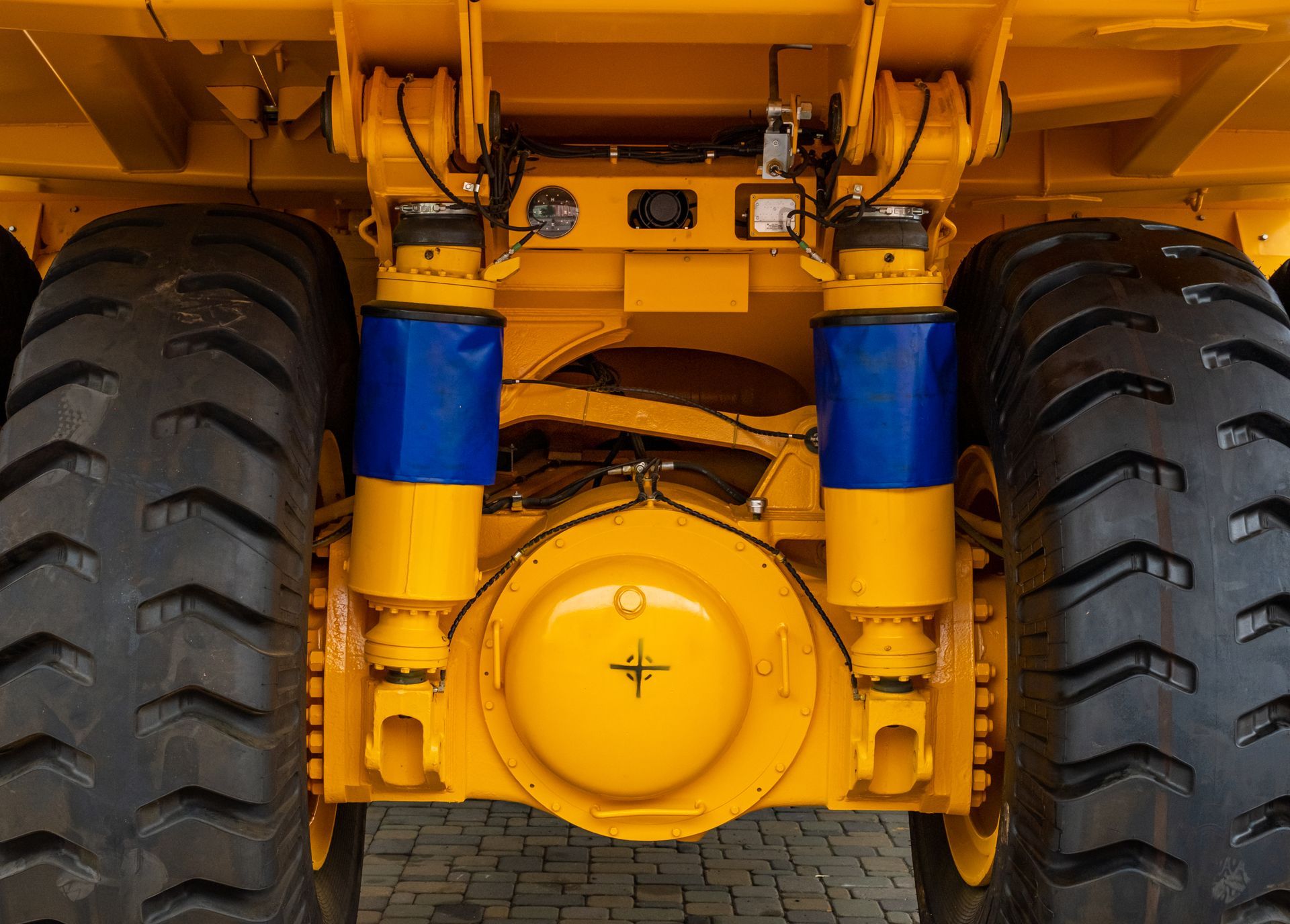 Close-up of a yellow heavy-duty vehicle’s front axle and large tires with blue suspension parts