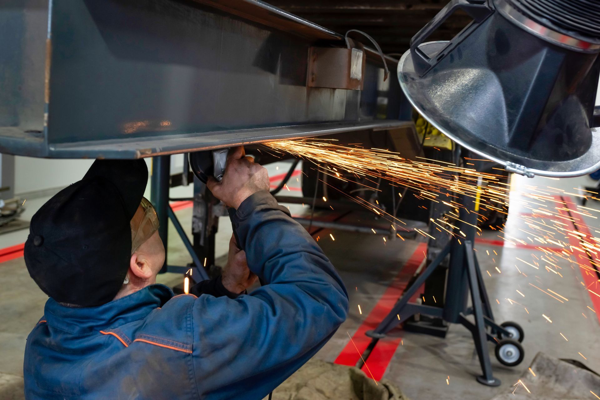 Mechanic welding under a vehicle, with sparks flying in a garage
