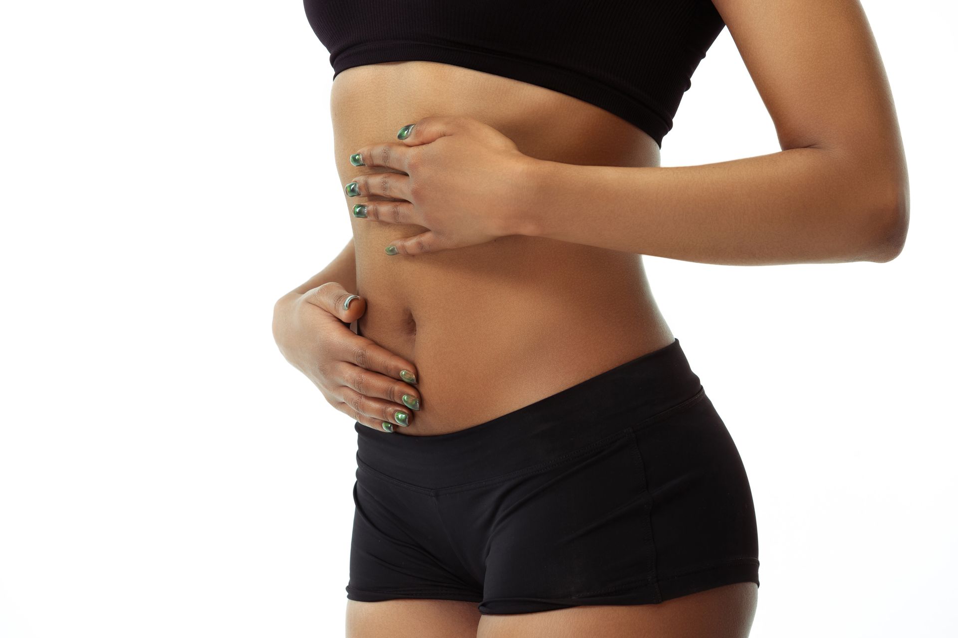 A woman in a black top and black shorts is holding her stomach