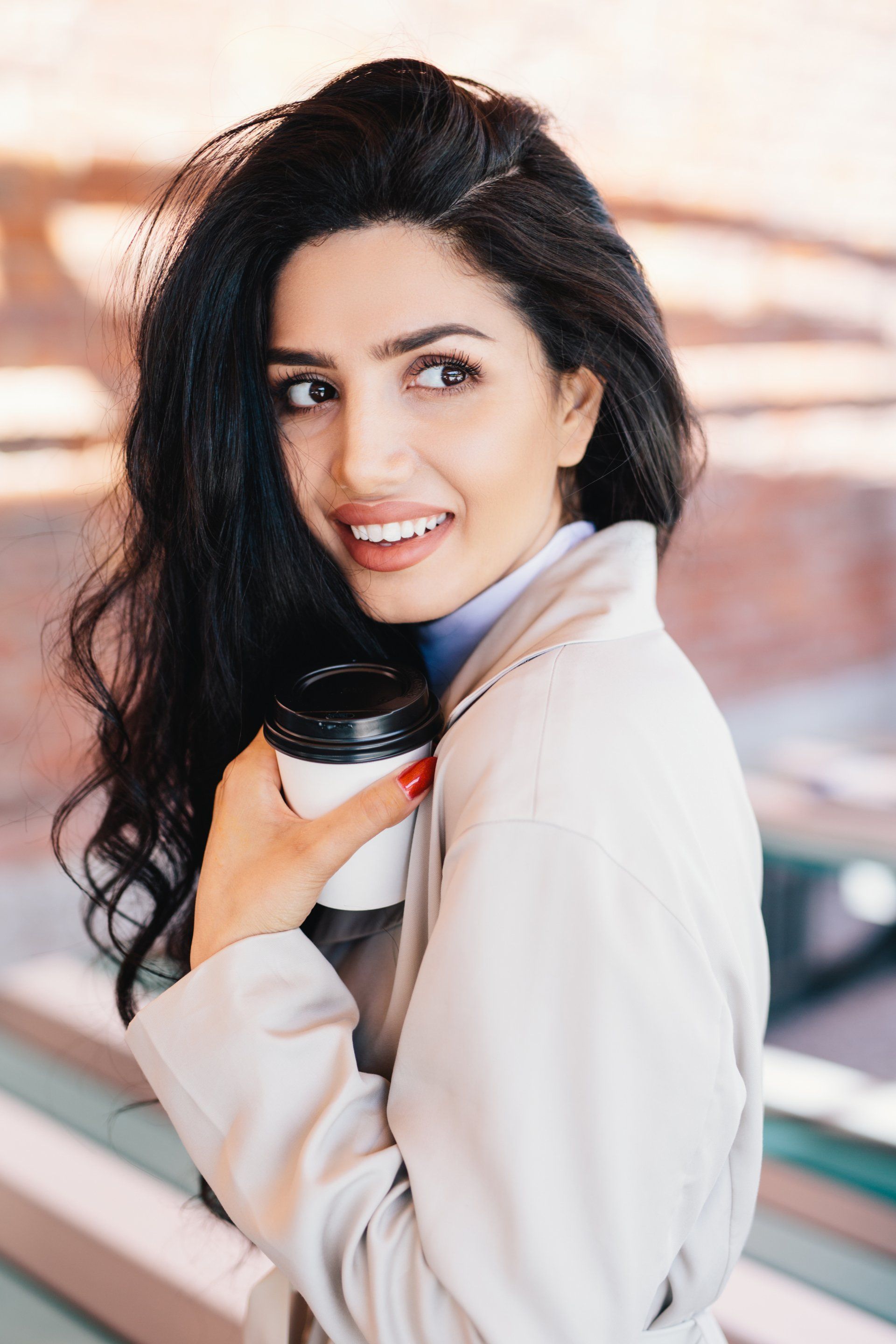 A woman is holding a cup of coffee and smiling.