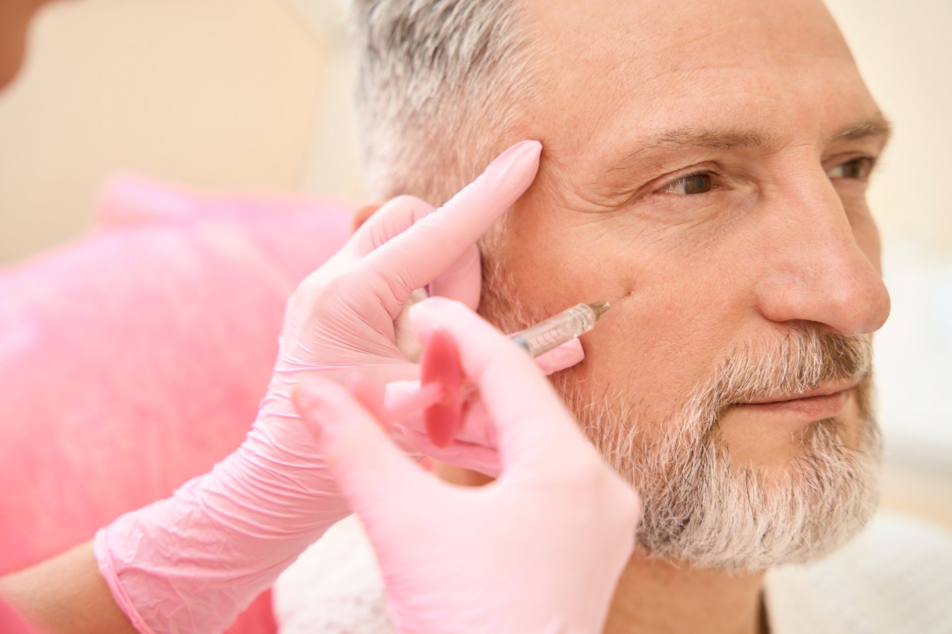 A man with a beard is getting a botox injection in his face.