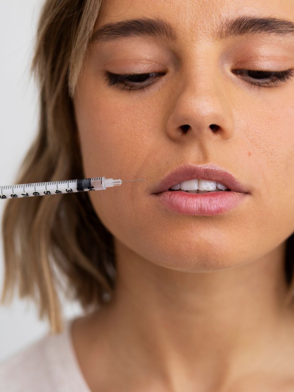 A woman is holding a syringe in her mouth.