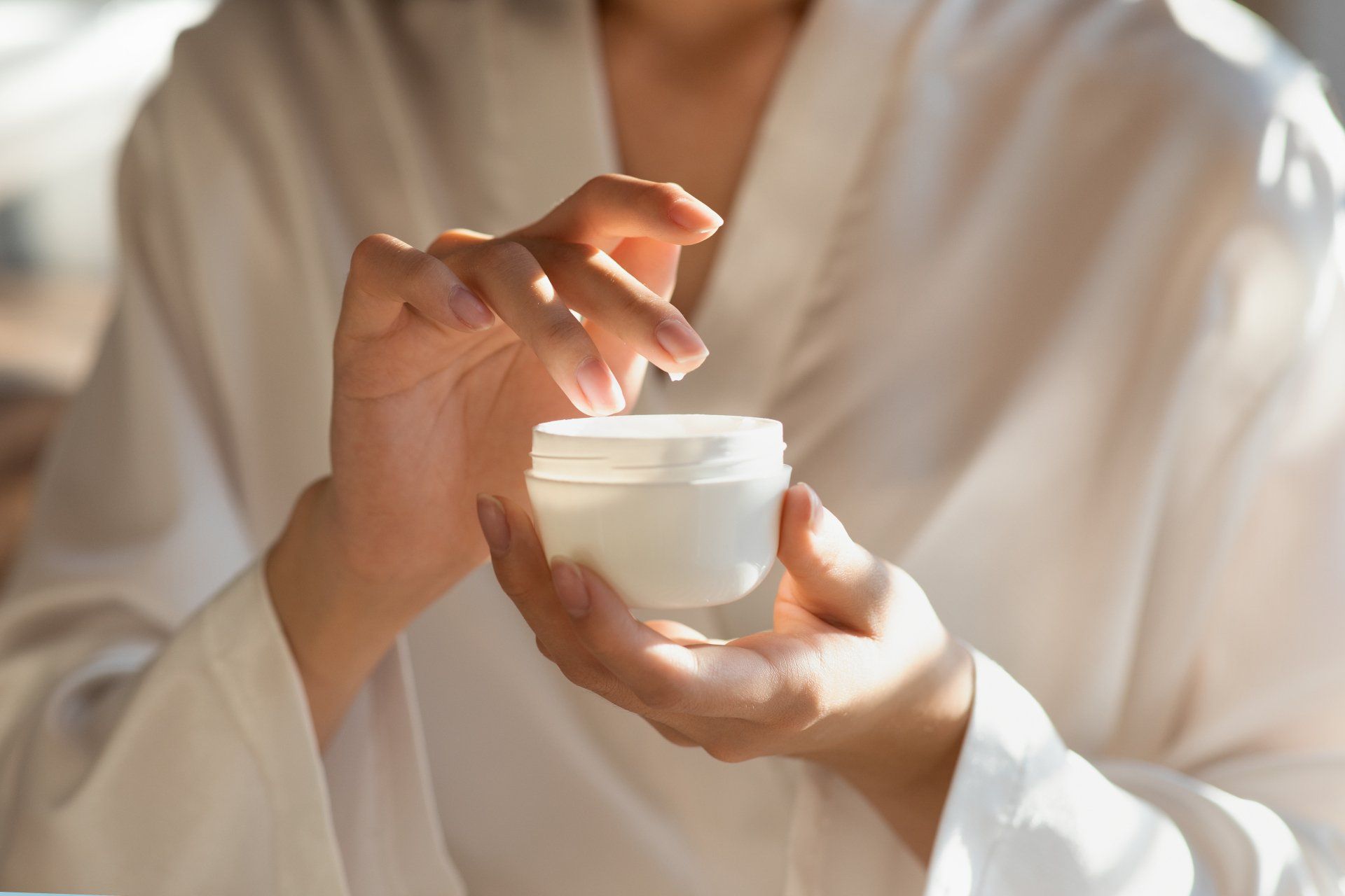 A woman is holding a jar of cream in her hands.