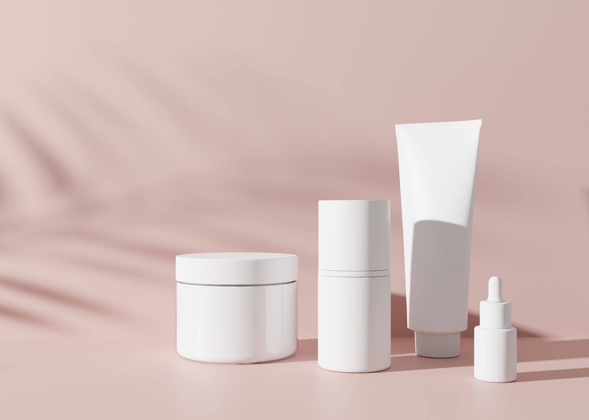 A group of white cosmetic containers on a pink background.