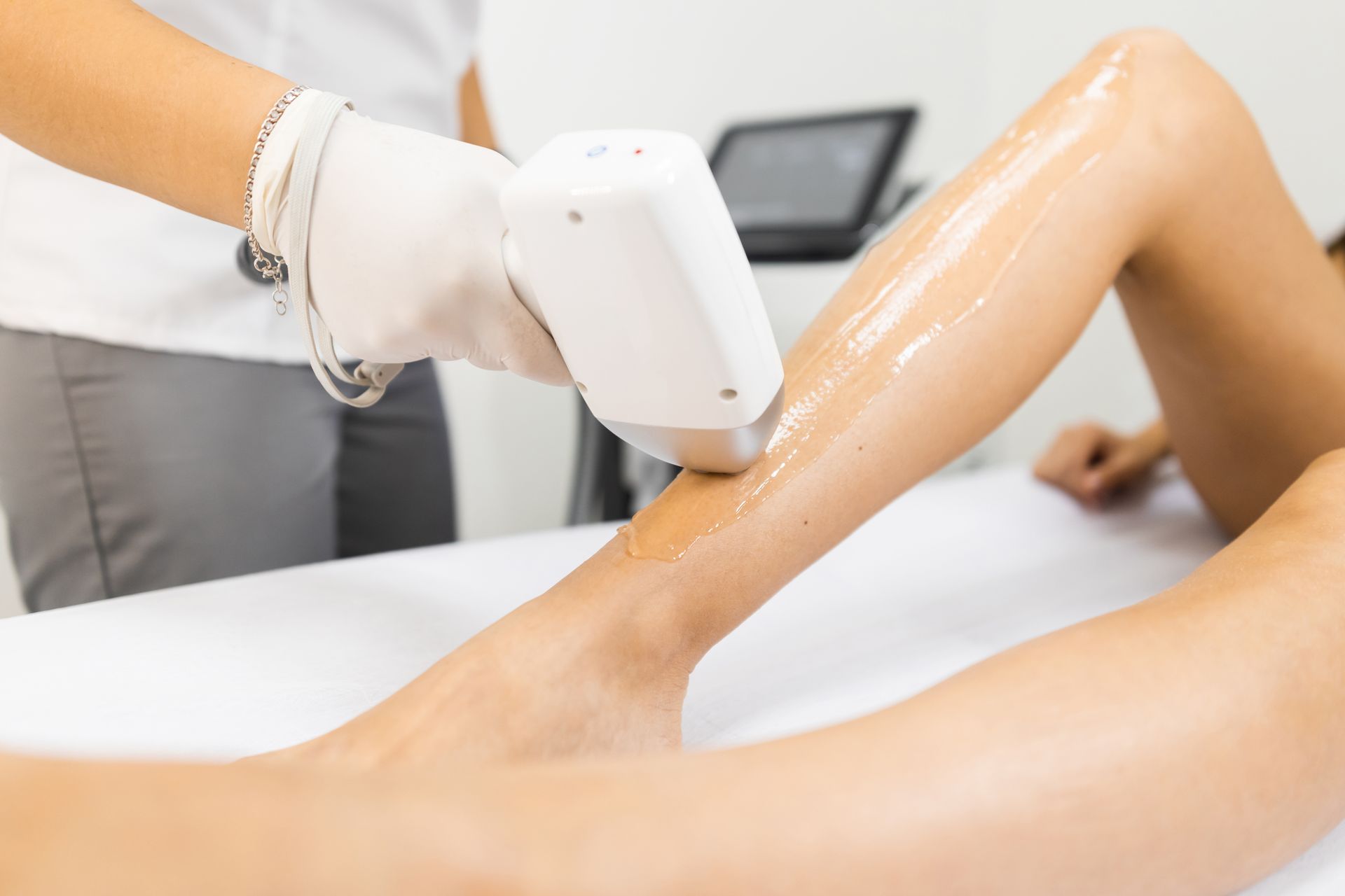 A woman is getting a laser hair removal treatment on her legs.