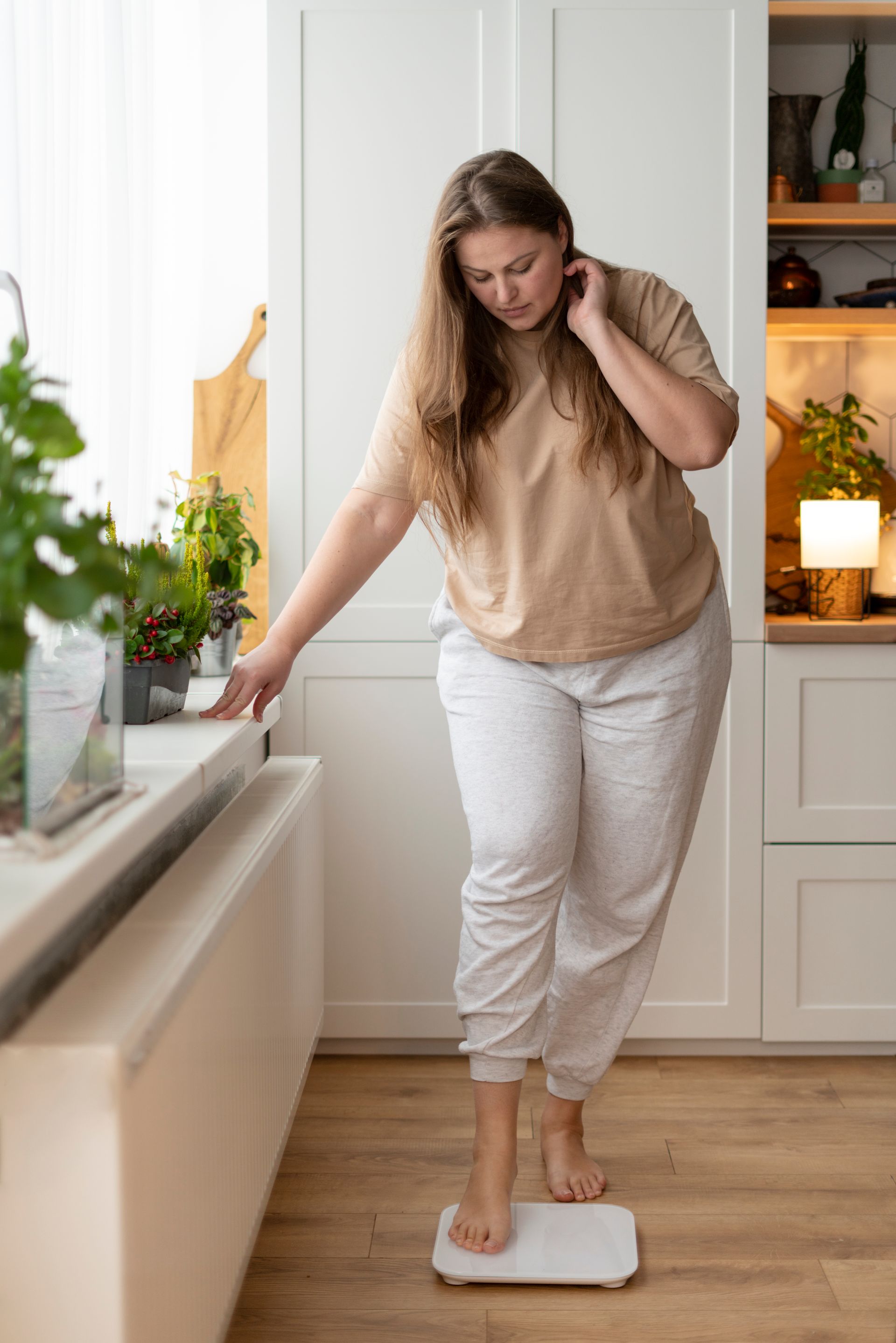 A woman is standing on a scale in a kitchen.