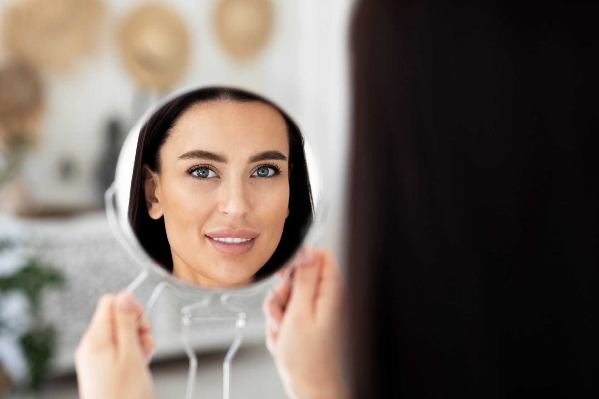 A woman is looking at her reflection in a mirror.