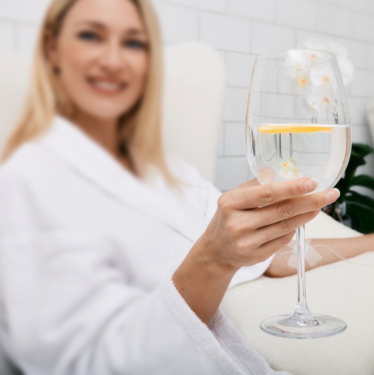 A woman in a bathrobe is holding a glass of wine