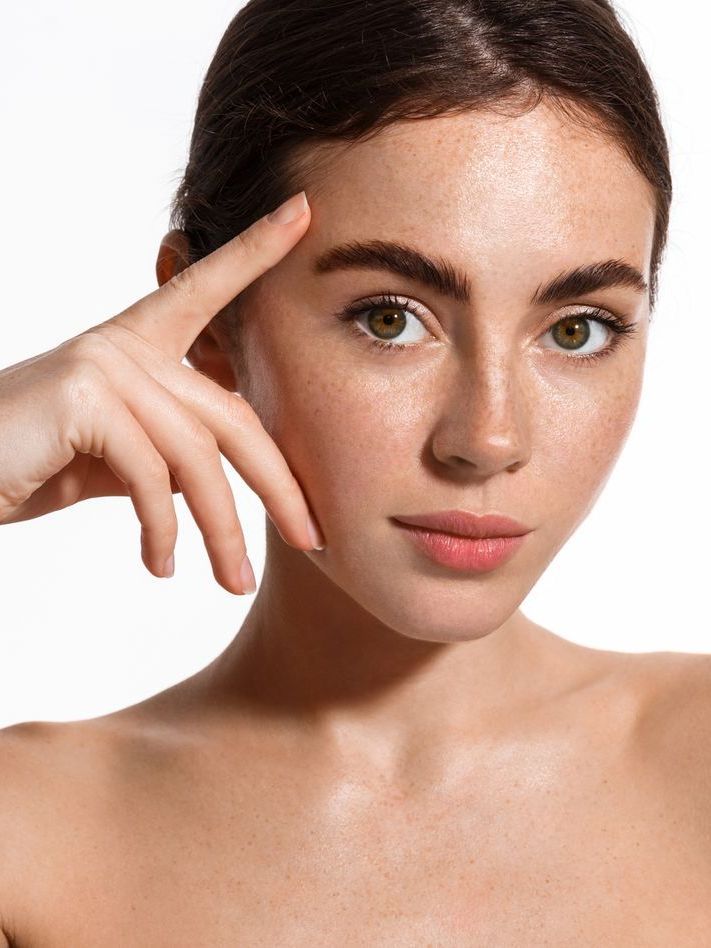 A close up of a woman 's face with her hand on her forehead.