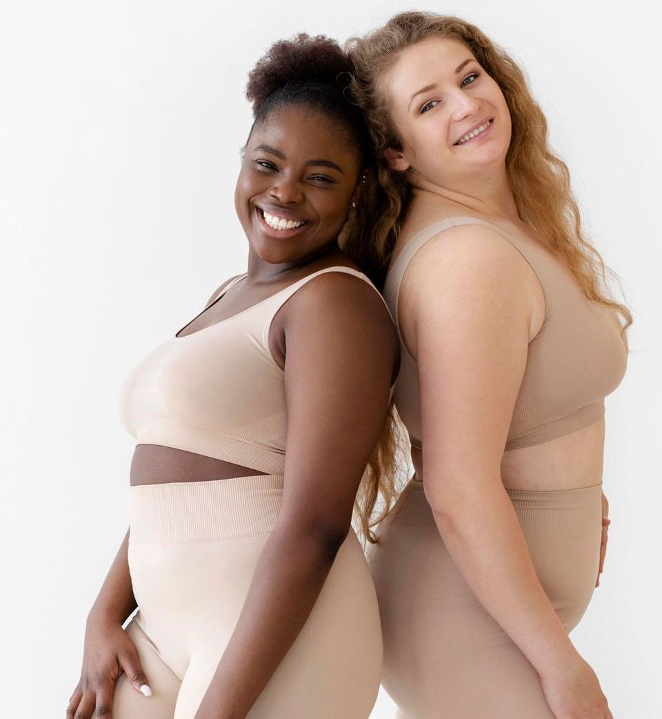 Two women are standing back to back and smiling.