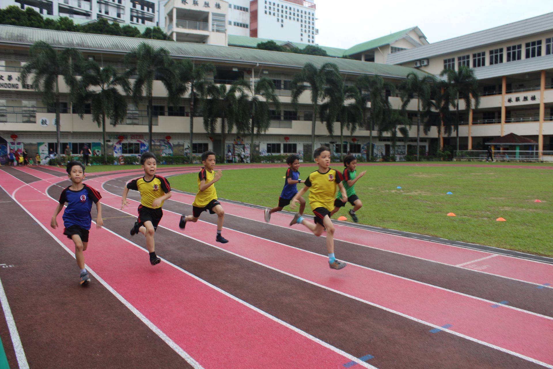 Students enthusiastically participating in a Sports Day sprinting event on the school’s running track.