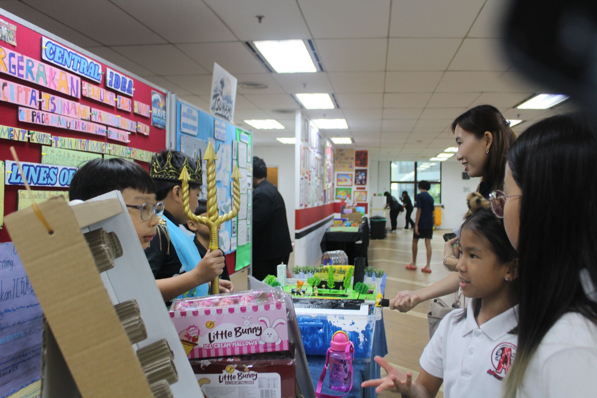 A student is presenting a creative project or model while wearing a costume and holding a decorative prop.