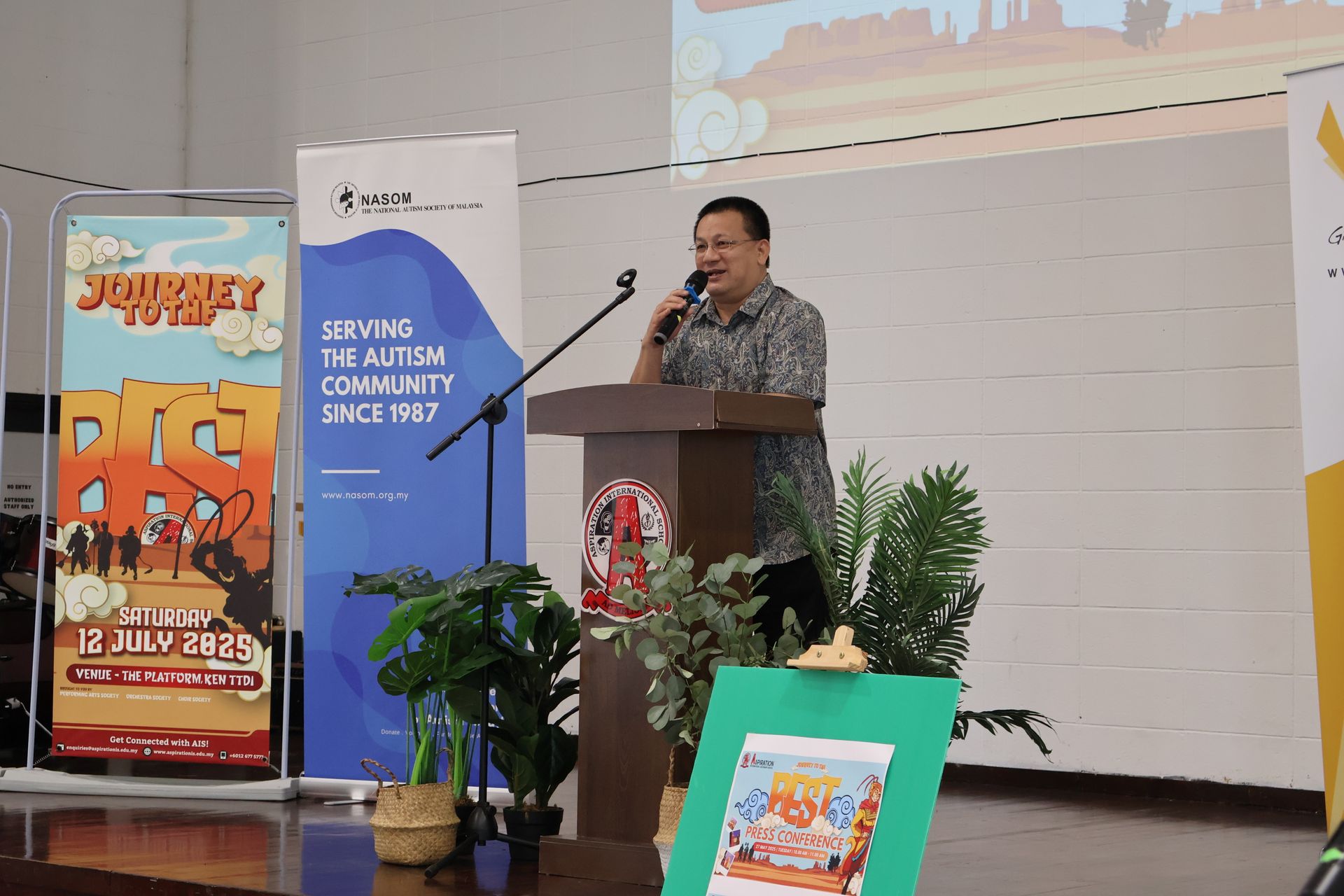 A person speaking at a podium during an event for the autism community, with event banners visible on a stage.