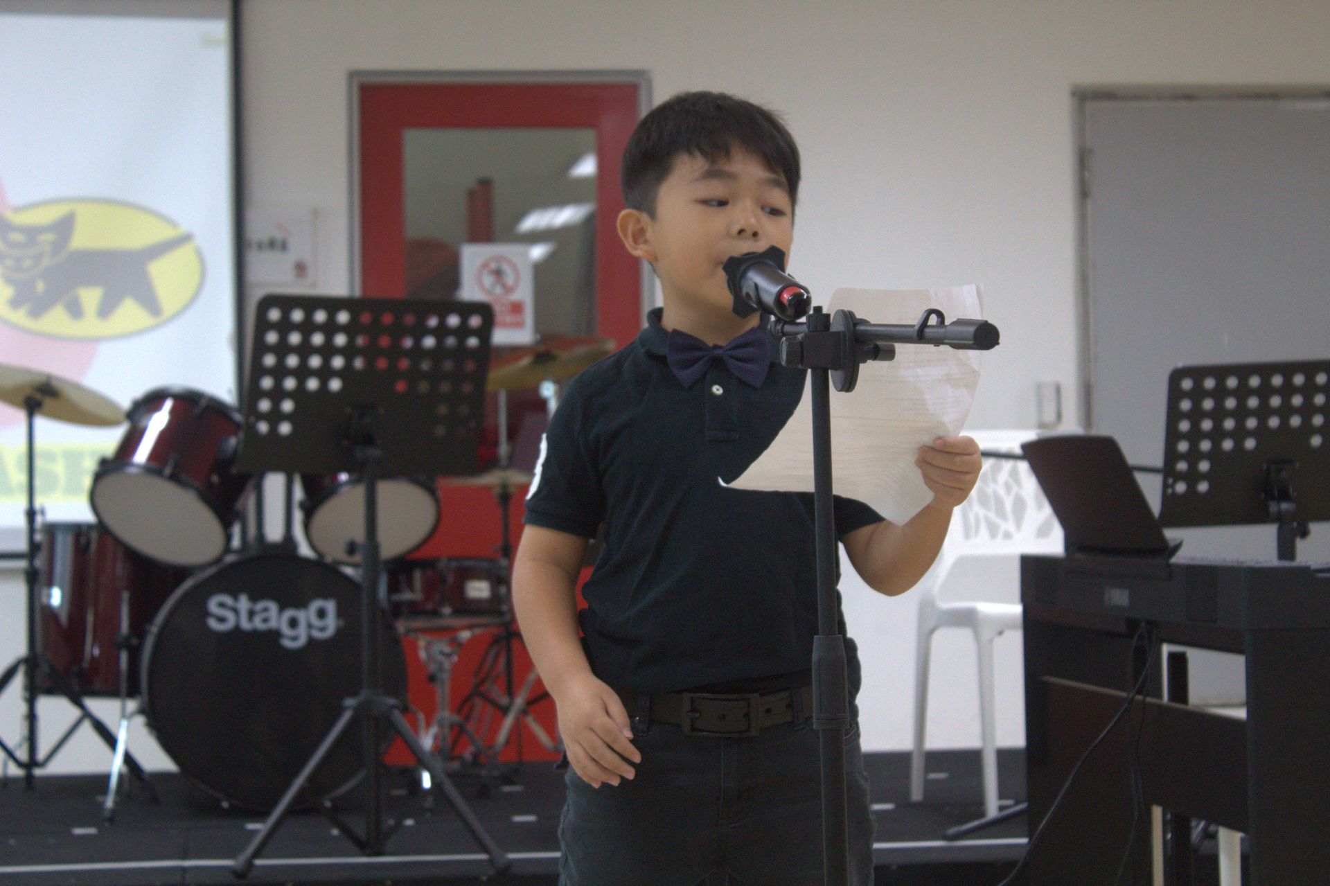 A primary student confidently participates in a school performance, demonstrating public speaking on stage.