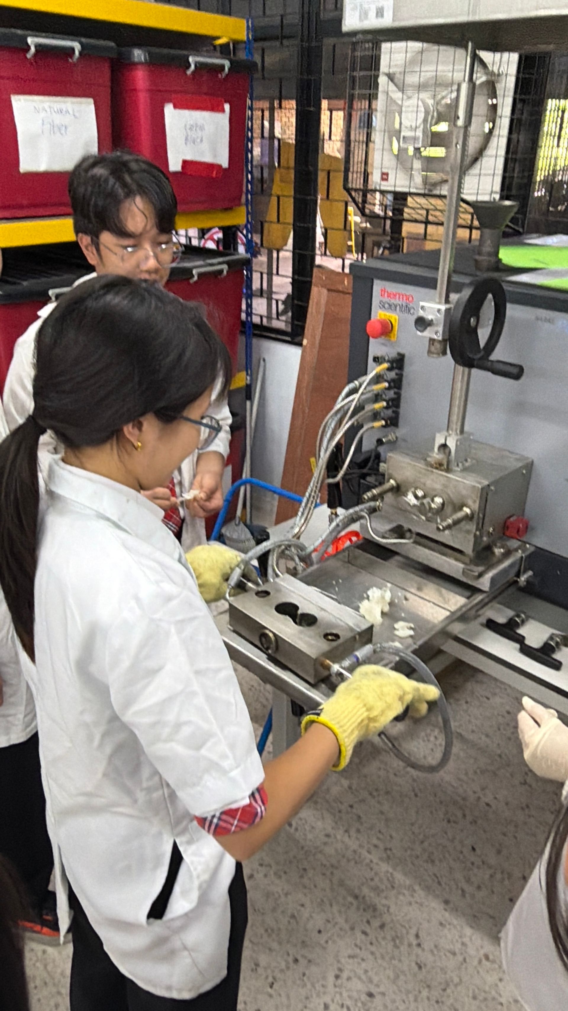 Students in a hands-on science engineering workshop operating a small industrial machine.