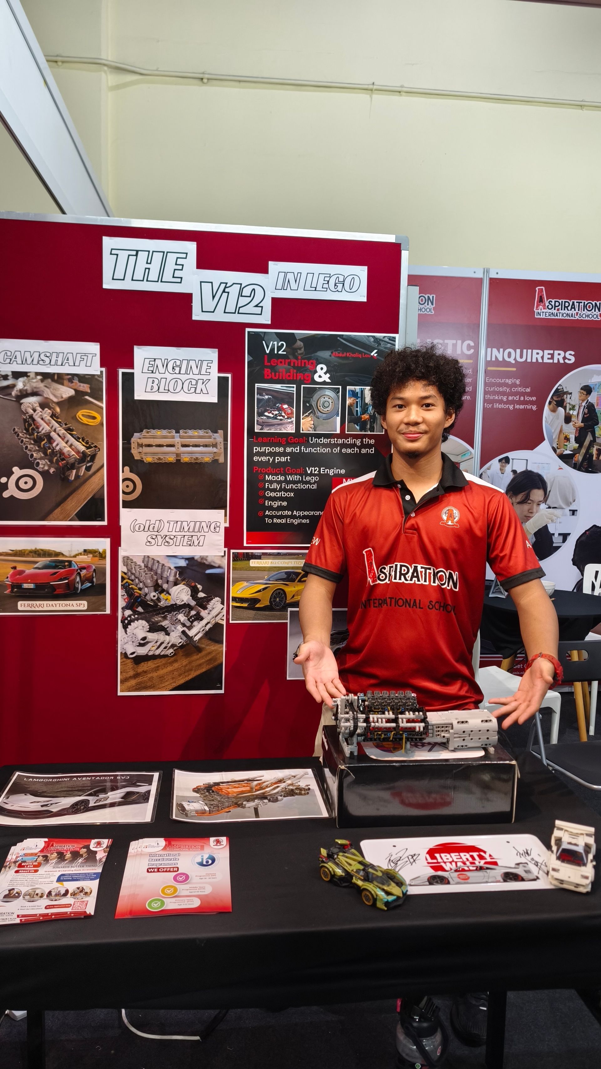 A student proudly presents a LEGO V12 engine model, showcasing creativity, engineering skills, and hands-on learning.