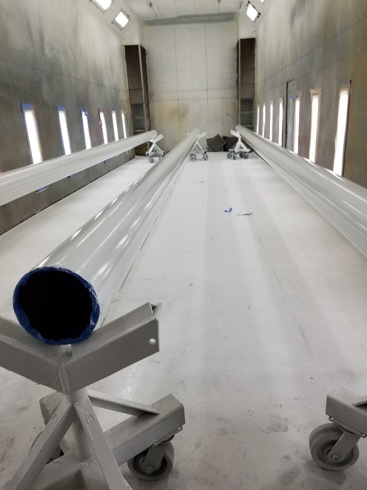 Empty industrial chamber with long white rails and a blue-capped pipe in the foreground