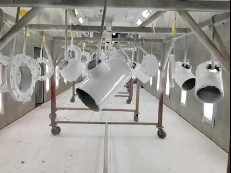 Hanging white painted parts on a conveyor line in an industrial spray booth
