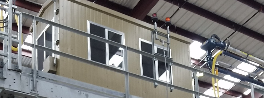 Industrial platform with workers in safety harnesses inspecting a metal structure inside a factory.