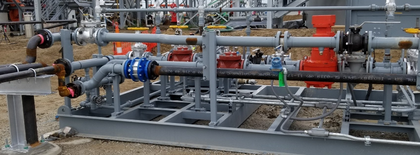 Industrial piping and valves in a factory setting with gray, red, and blue components.