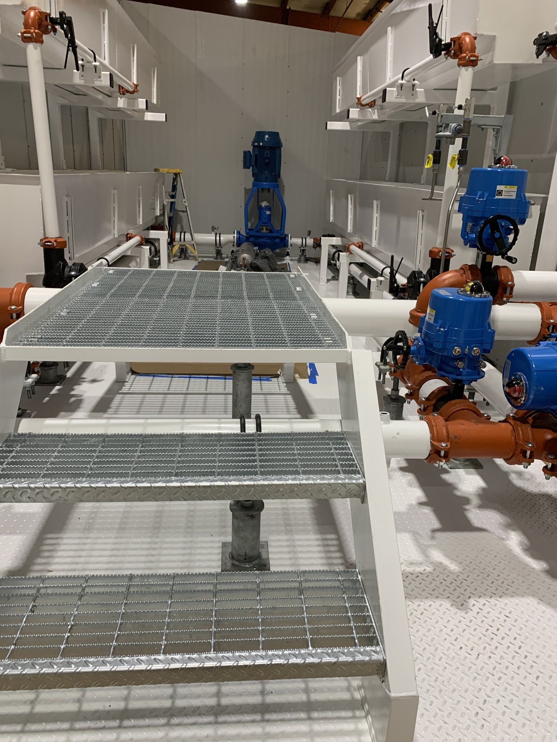 Industrial robot arms around a metal worktable in a white factory room.