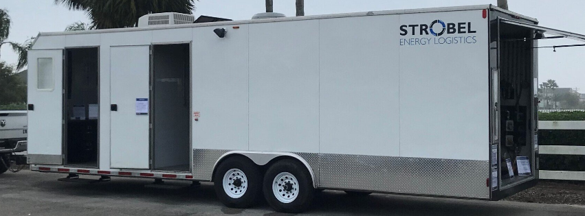 White Strobel mobile trailer with black trim and tandem wheels parked outdoors.