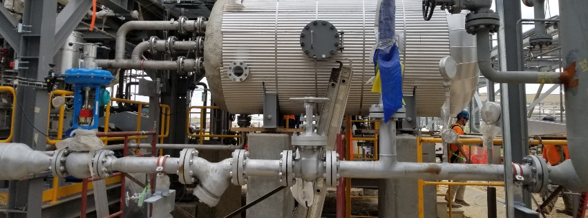 Industrial plant with silver tanks, pipes, and valves in a factory setting