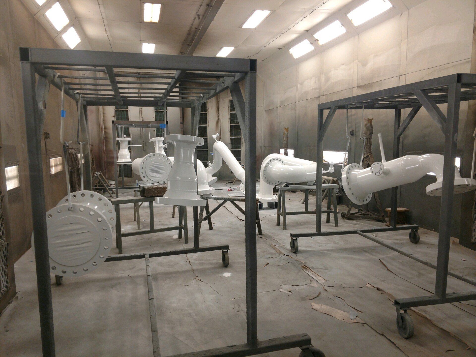 Industrial workshop with white parts mounted on black metal frames in a concrete room.