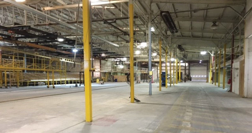 Empty industrial warehouse interior with yellow support columns and concrete floor