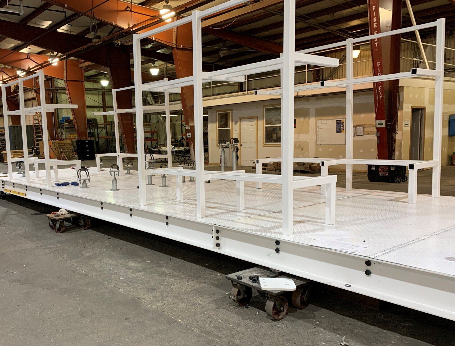 White metal platform frame on wheels inside an industrial warehouse workshop