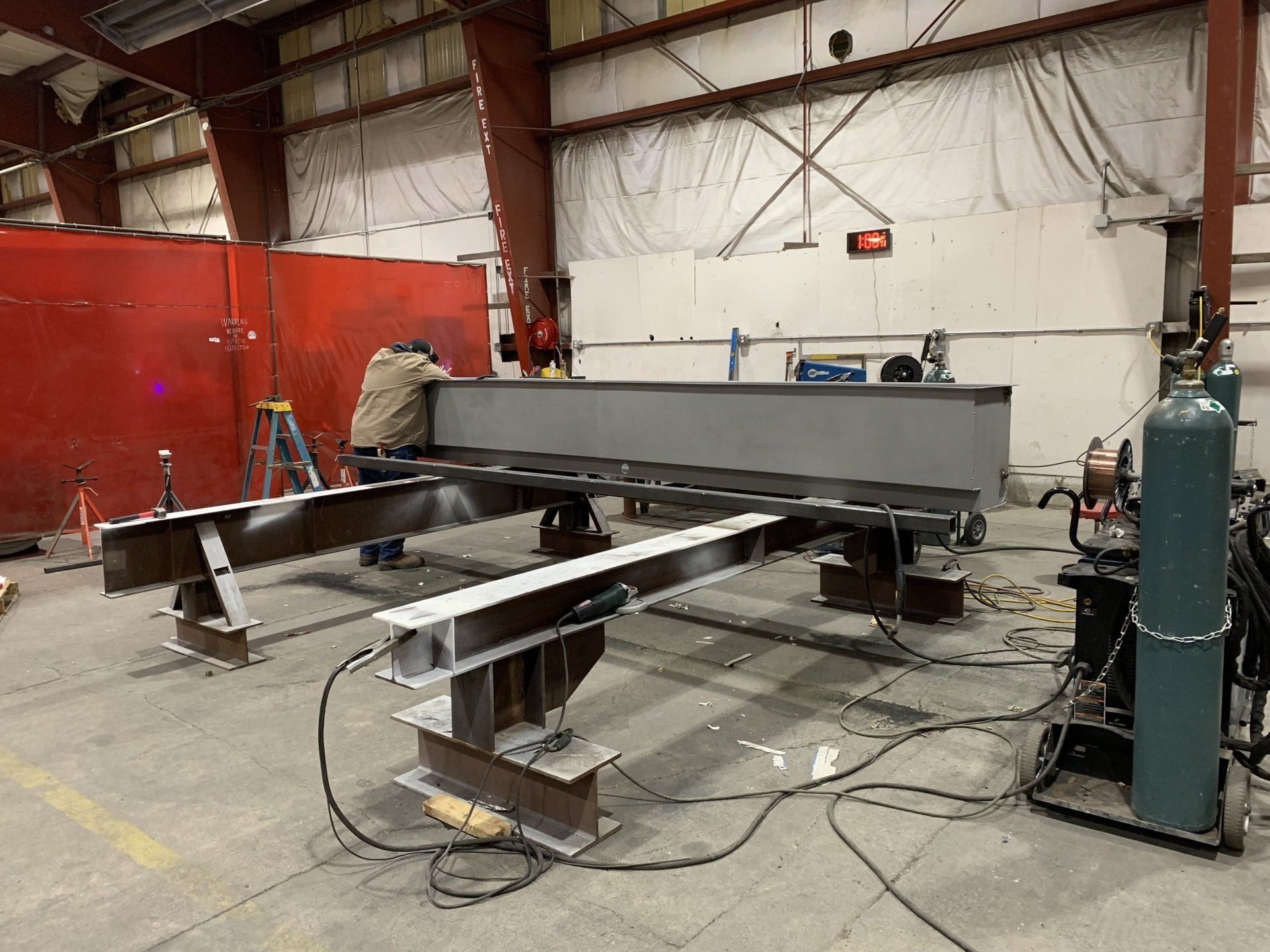 Industrial workshop with a large metal machine frame, red partition walls, and cables on the floor.
