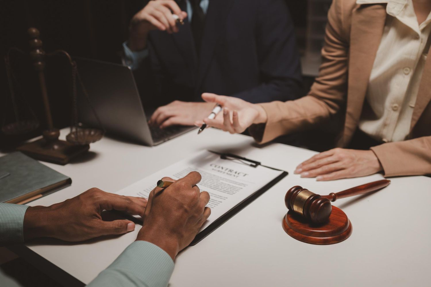 Lawyers reviewing a contract at a table with a gavel and laptop