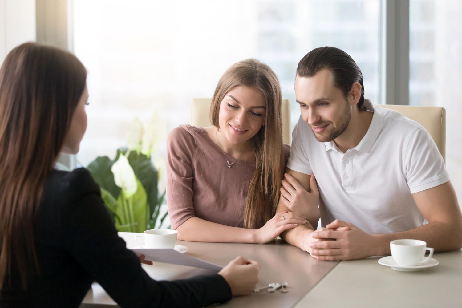 Three people in a meeting, two smiling at a table with a coffee cup nearby