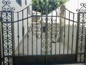 Ornate black and gold gate, topped with an eagle, reads 
