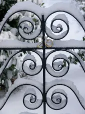 Snow-covered wrought iron gate with address 