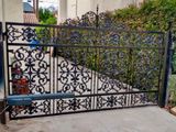 Black wrought-iron driveway gate with ornate scrollwork
