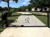 Black wrought iron driveway gate with an ornate arch, 