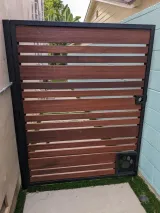 iron gate with horizontal slats, black frame, and a pet door with paw print, between walls.