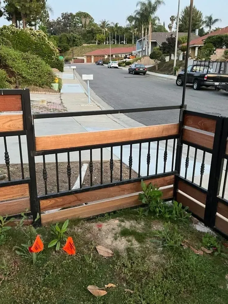 Fence with iron and metal detailing bordering a residential street.
