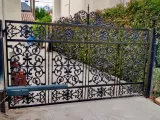 Black wrought-iron driveway gate with ornate scrollwork