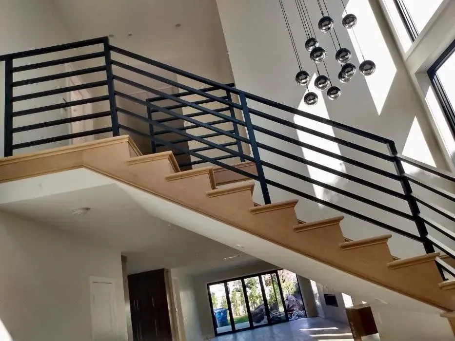 Staircase with wooden steps and black metal railing in a bright, modern home.