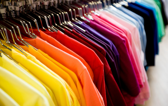 A row of colorful shirts hanging on a rack in a store.