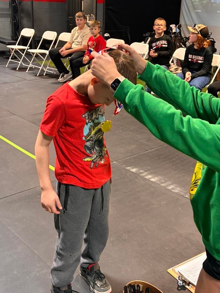 Person receiving a medal at an event. Others watch in the background.