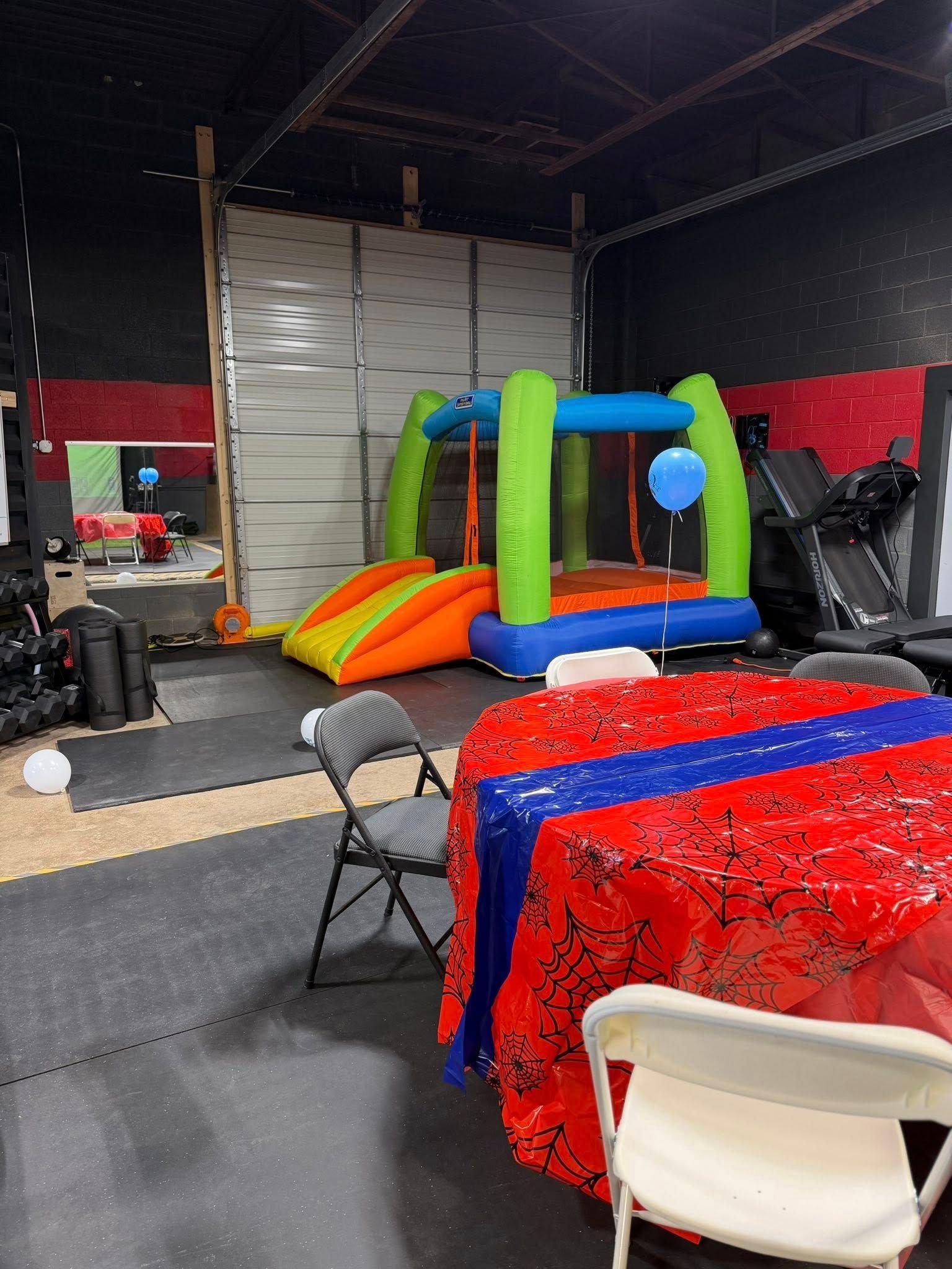 Indoor space with a bounce house, decorated table, and exercise equipment.